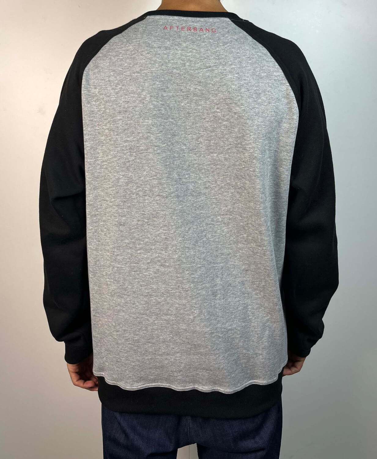 Sudadera sin capucha Raglan gris con mangas negras. Mini logo bordado en color rojo.