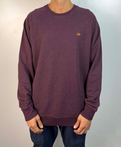 Sudadera Crewneck color vino. Mini logo bordado en el pecho izquierdo en color naranja. Corte Raglan.